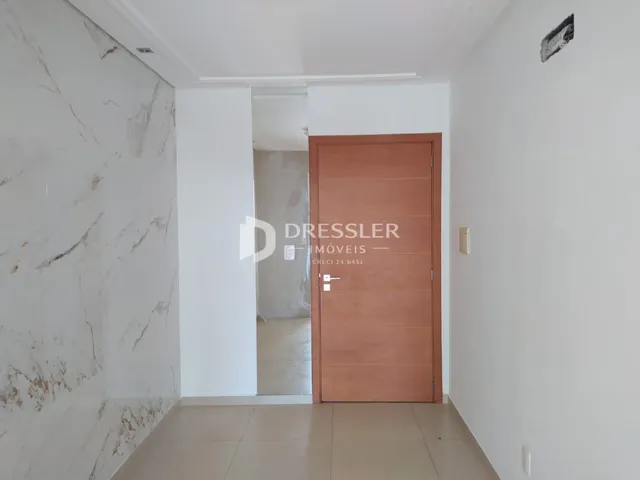 A passagem interna da propriedade apresenta paredes brancas e piso claro.