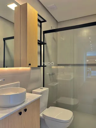 Interior de um banheiro moderno com bancada e box de vidro.