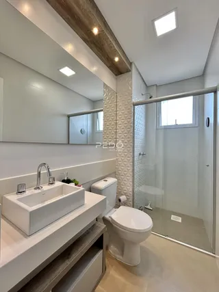 Banheiro moderno com bancada de pia e box de vidro.