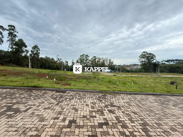 Vista externa de um terreno gramado com pavimentação de blocos.
