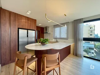 Cozinha moderna com ilha e armários de madeira em um apartamento.