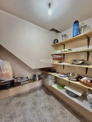 Vista interna de uma cozinha com prateleiras de madeira e utensílios de metal.