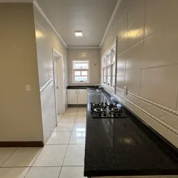 Hall de corredor com paredes brancas e piso de cerâmica.