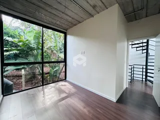 Sala com grande janela de vidro que oferece vista para a vegetação externa.