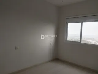 Vista interna de um cômodo com paredes brancas e piso de madeira clara.
