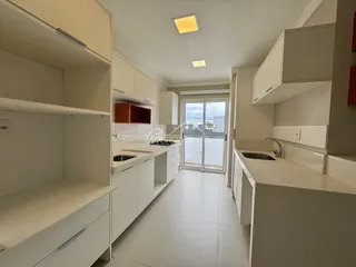 Cozinha moderna com armários brancos e piso claro, com acesso a uma área externa.