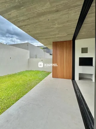 Vista externa mostrando um pátio com gramado e uma parede de madeira.