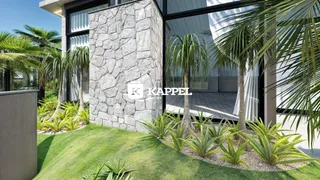 Fachada de uma residência com paisagismo verde e palmeiras.