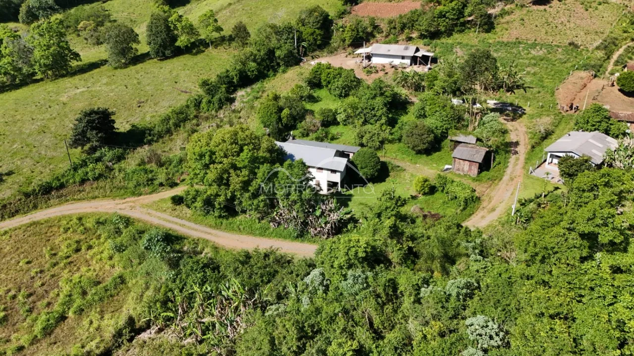 Vista aérea de uma propriedade rural em uma área verde e arborizada.