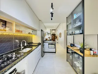 Cozinha moderna com armários brancos e bancada escura.