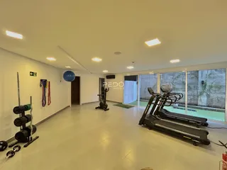 Imagem de uma sala ampla com equipamentos de ginástica e grandes janelas.