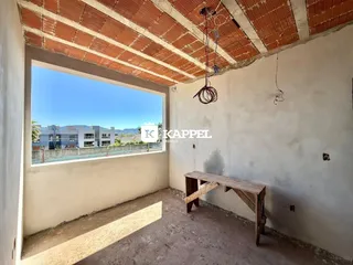 Vista da sala com teto de tijolos aparentes e uma grande janela para a paisagem.