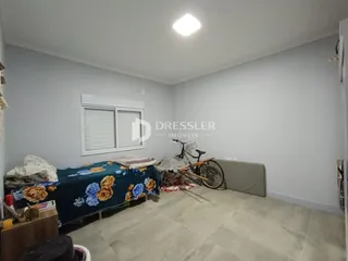 Quarto com cama e janela em ambiente claro.