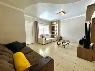 Sala de estar com sofá e piso de cerâmica em um imóvel no Brasil.