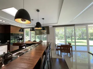 Cozinha moderna com ilha de madeira escura e grandes janelas que dão para o jardim.