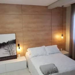Quarto com cama de casal e cabeceira de madeira.