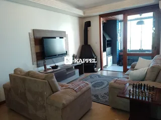 Sala de estar com sofá e televisão em um ambiente claro com piso de madeira.