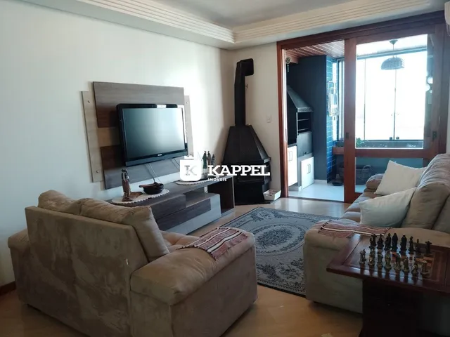 Sala de estar com sofá e televisão em um ambiente claro com piso de madeira.