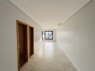 Corredor interno de uma residência com paredes brancas e piso claro.