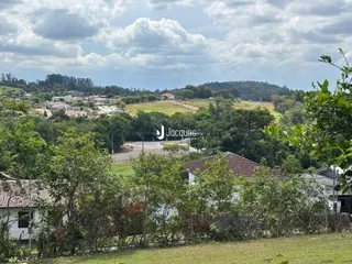 Vista panorâmica de paisagem rural com vegetação densa e casas ao fundo.