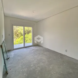 Ambiente interno de uma sala com piso de concreto cru e porta de vidro voltada para a natureza.