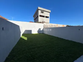 Parede branca alta com gramado verde em frente a uma estrutura de concreto.