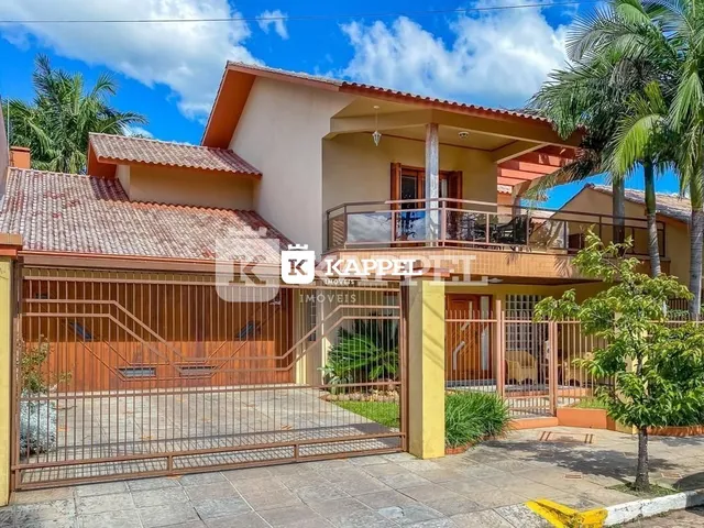 Fachada de uma residência em Lajeado, Brasil, com portão de metal e telhado de telhas.