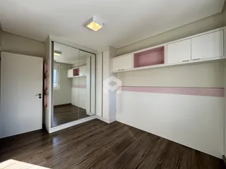 Sala de estar com piso de madeira e armários brancos.