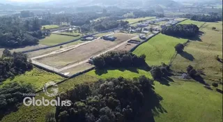Vista aérea de uma propriedade rural com campos e vegetação ao redor.