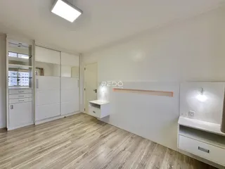 Ambiente interno de um cômodo com piso de madeira clara e armários brancos.