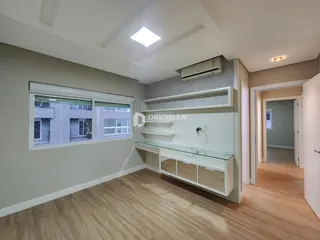 A sala apresenta piso de madeira clara e uma grande janela com vista para o exterior.
