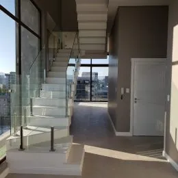 Foto de um corredor com escadaria e grandes janelas.