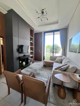 Sala de estar moderna com sofá e poltronas de couro e acesso a uma área externa.