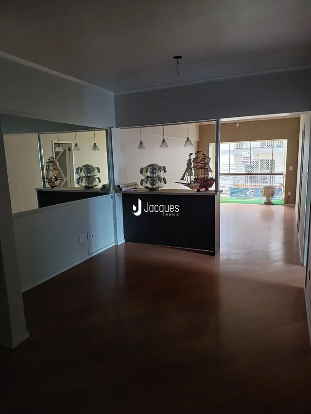 Sala de estar com piso de madeira e portas de vidro que dão acesso a outra área.