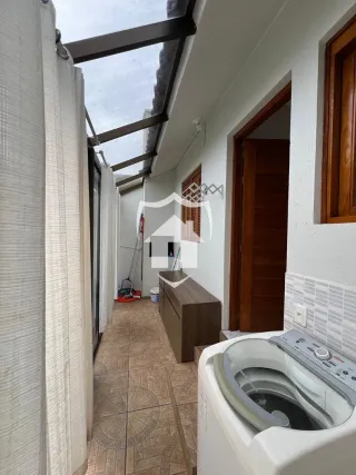 Corredor interno com piso de cerâmica e molduras de madeira em uma residência.