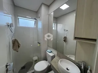 Interior de um banheiro com box de chuveiro e louças sanitárias.