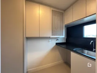 Cozinha com armários brancos e bancada escura.