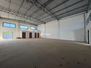 Vista interna de um grande espaço industrial com piso de concreto.