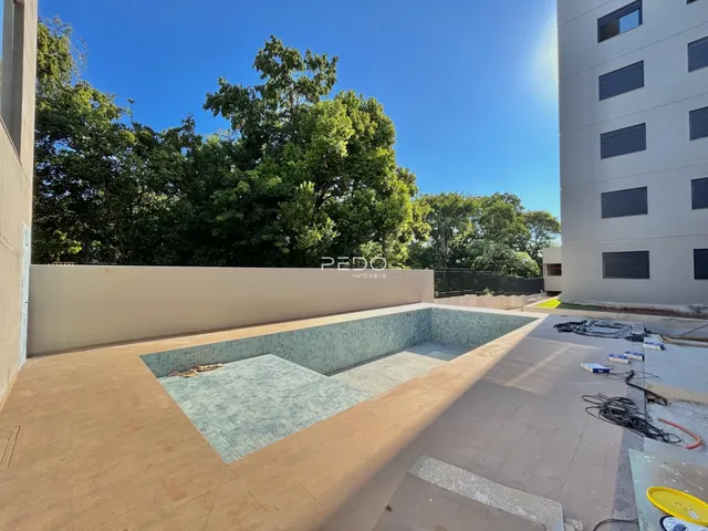 Área externa com muro e vegetação ao lado de um edifício residencial.