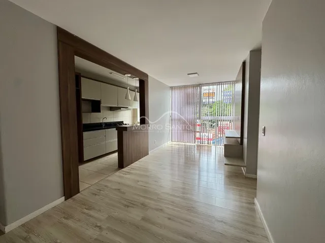 Sala de estar com piso de madeira clara e vista para a área externa.