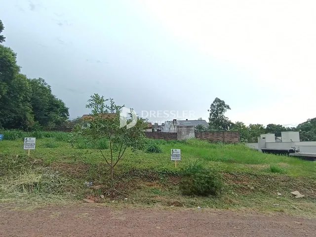 Vista externa de um terreno com vegetação e sinais no primeiro plano.