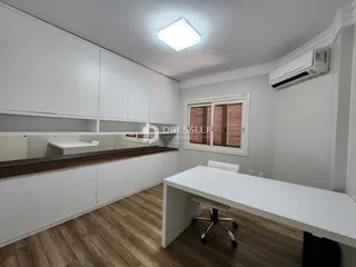 Interior de uma cozinha moderna com armários brancos e piso de madeira.
