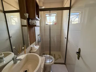 Banheiro com pia, vaso sanitário e box de vidro.