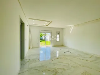Ambiente interno amplo com piso de mármore claro e paredes brancas.