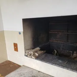 Foto de um nicho escuro com lareira em uma parede interna.