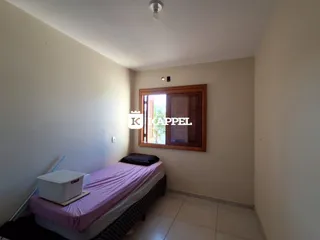 Quarto com cama e janela de madeira visível.