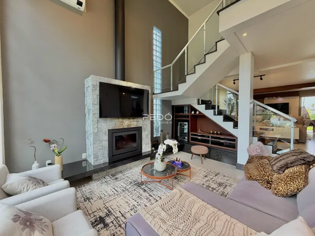 Sala de estar moderna com lareira e escadaria em um imóvel em Lajeado.