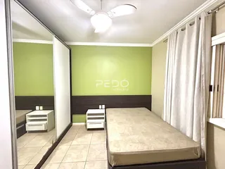Quarto com paredes verdes e móveis brancos.
