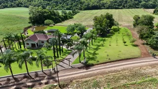 Vista aérea de uma residência com amplo jardim e área rural no interior do Brasil.