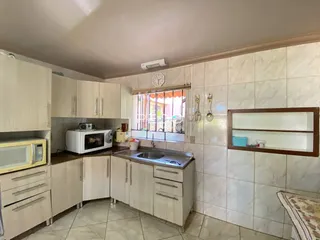 Foto de uma cozinha com armários brancos e revestimento de azulejos claros.